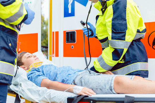 Sanit&auml;ter messen Blutdruck von verletztem Jungen vor Krankenwagen