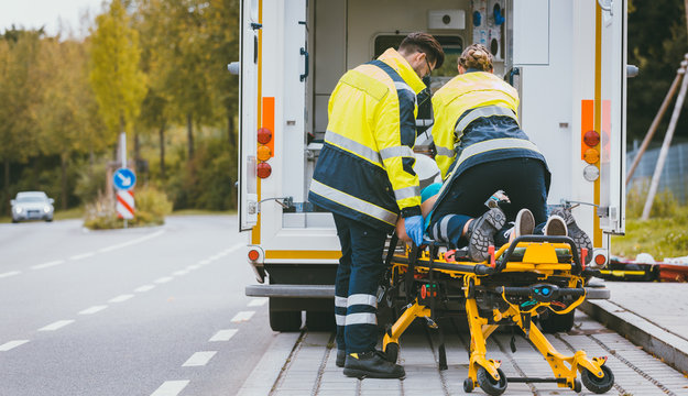 Sanit&auml;ter schieben Frau in Rettungswagen auf Transportliege 