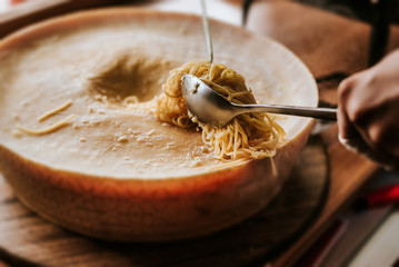 Spaghetti pasta inside a cheese wheel. Close-up.