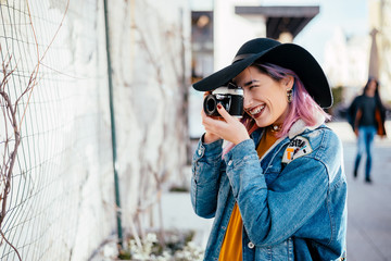 Young hipster photographer taking a photo at city street.
