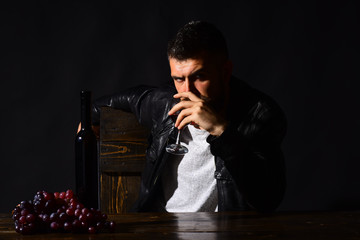Man with beard drinks glass of wine on brown background