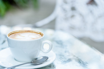 A white cup of coffee and laptop ready to working in the morning with relaxing and yellow lighting bokeh background.