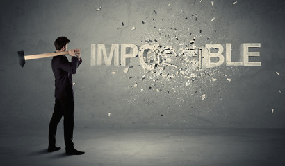 Business man hitting impossible sign with hammer