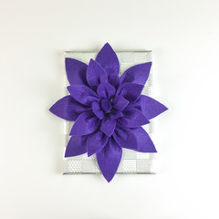 Homemade felt purple flower centerpiece with cup holders and napkin holder on white background - top view