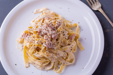 close up of pasta carbonara, on a white plate with background