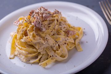 close up of pasta carbonara, on a white plate with background