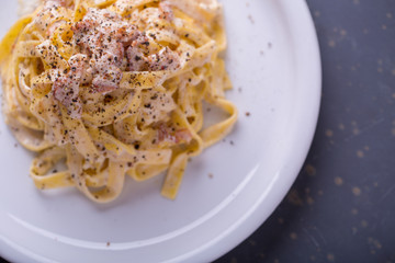 close up of pasta carbonara, on a white plate with background