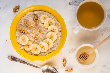 Oatmeal with banana and honey. Porridge in a yellow bowl top view