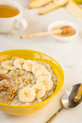 Oatmeal with banana and honey. Porridge in a yellow bowl