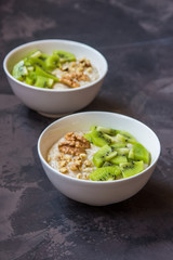 Oatmeal with kiwi fruit and walnuts. Two bowls porridge