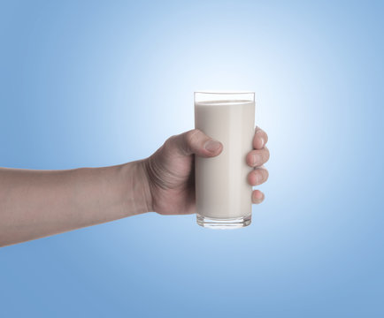 Hand Holding Glass Of Milk On Blue Background