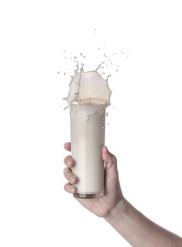 Hand holding glass of milk with a splash isolated on a white background