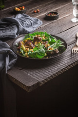 Green salad with liver and spinach on dark rustic background.