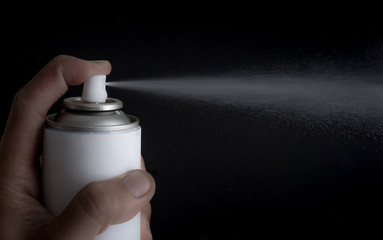 Hand holding an spray on dark background,snow spray