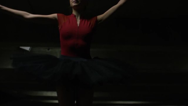 Handheld shot of ballet dancer on pointe in a car park, in slow motion
