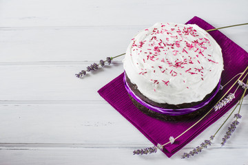 Traditional Easter panettone or russian kulich with icing and lavender on violet napkin and white wooden table. Easter baking.