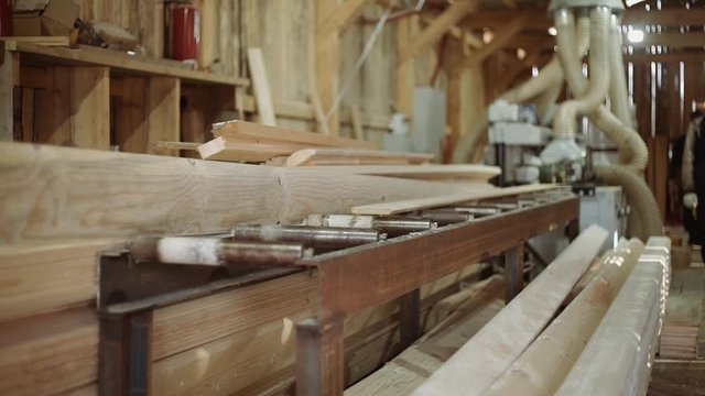 Wood board running out carpenter refiner machine at sawmill factory, lots of sawdust