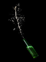 Green beer bottle opening with exploding and splashing on dark background