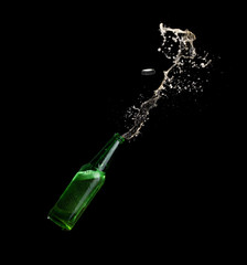 Green beer bottle opening with exploding and splashing on dark background
