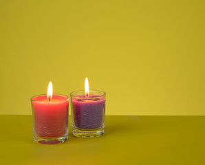 Obraz na płótnie Canvas Aromatherapy Candles in glass with text space against yellow background