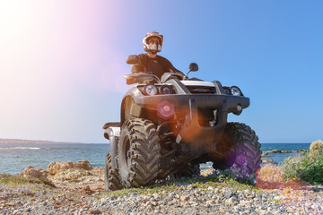 A man is driving ATV on off-road. Sunny.
