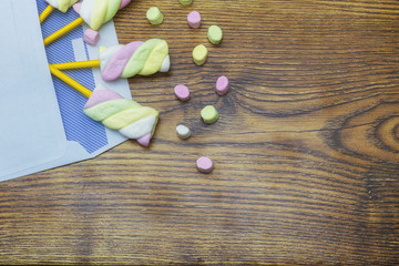 Colorful marshmallows in the envelope wooden studio background