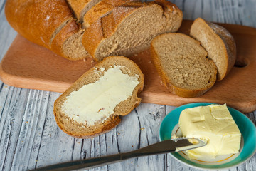 A slice of rye bread with butter on a wooden background is a close-up.