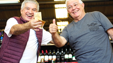 Satisfied Senior Friends Thumbs Up in Supermarket with Brazilian Currency