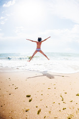 A girl is jumping on the beach.