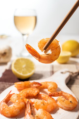 Fried shrimps with chopsticks on a white wooden board