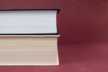 Two hardcover books on each other on a red background. White and black book.