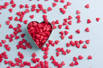 Metal and red hearts on blue cardboard or paper background.