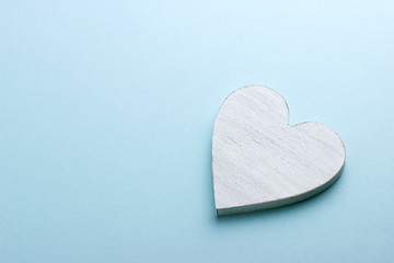 White wooden heart on blue cardboard background.