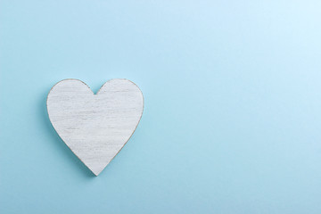 White wooden heart on blue cardboard background.