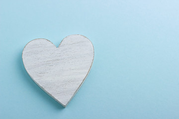 Obraz premium White wooden heart on blue cardboard background.
