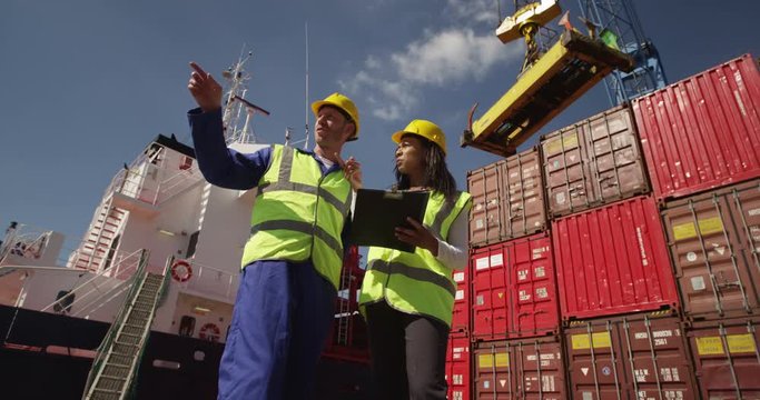 Dock workers discuss logistics at the harbor amidst shipping industry activity. Shot on RED Epic.