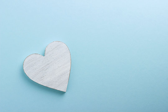 White wooden heart on blue cardboard background.