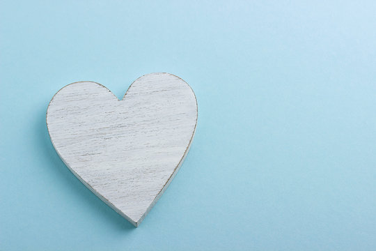 White wooden heart on blue cardboard background.