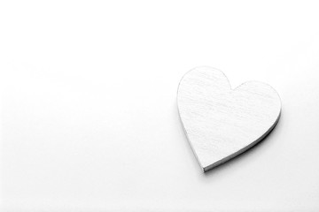 White wooden heart on black and white cardboard background.