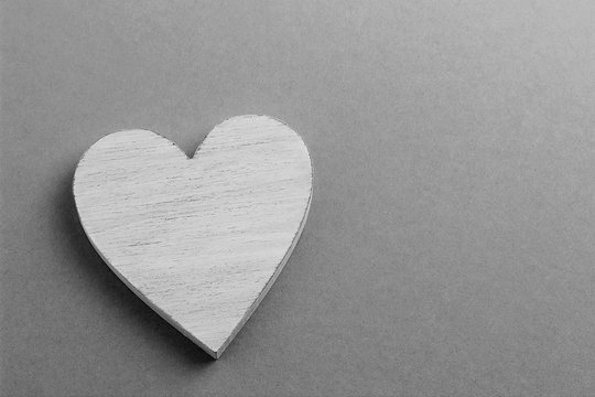 White wooden heart on black and white cardboard background.