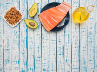 Piece of fresh salmon on a plate, avocado, almonds and sunflower oil on a table