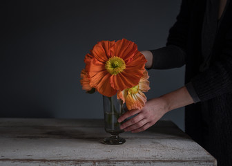 Frau dekoriert Blumen in einer Glasvase auf einem Tisch
