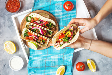 Female hands hold mexican pork tacos with vegetables. Tacos al pastor on wooden blue rustic...