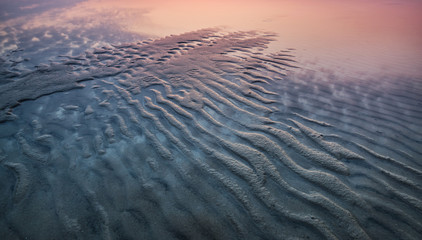Sand on the seashore during sunset. Beautiful natural seascape in the summer time