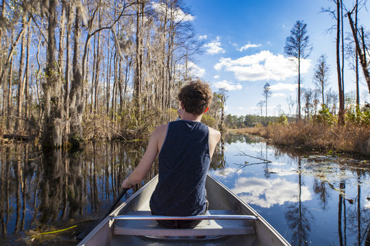 POV shot of canoe with teen paddling in Okefenokee swamp.