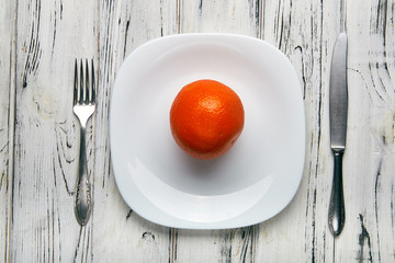 Eating for a girl, women on a strict diet. Bright red sunny orange on a white plain plate. Too little food for losing weight. Anti-obesity diet by evil nutritionist.