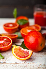 Bloody red oranges slices with leaves on wooden background