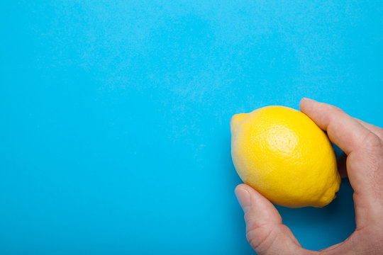 Portion of vitamins in the hand - yellow lemon on a blue background.