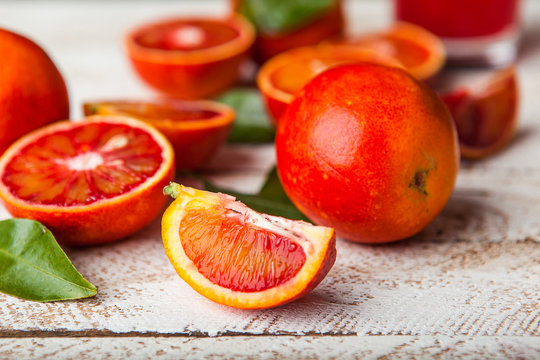 Bloody red oranges slices with leaves on wooden background
