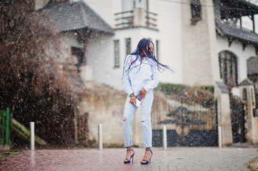 Stylish african american girl with dreads holding mobile phone at hand, outdoor snowy weather.